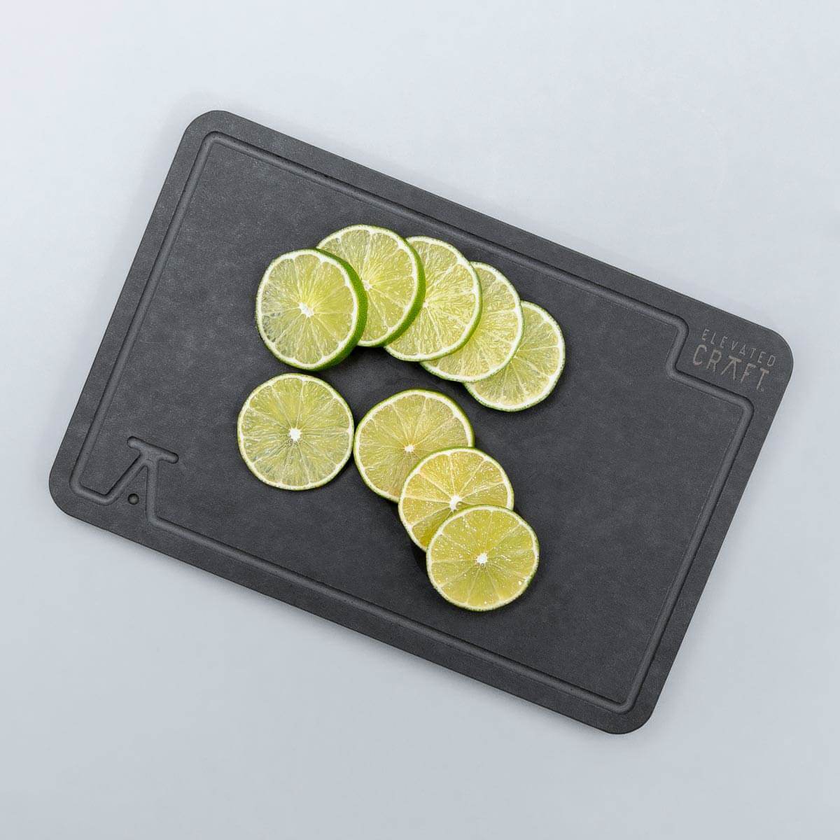 Photo of cut limes on a white marble counter using the elevated craft wood fiber garnish board