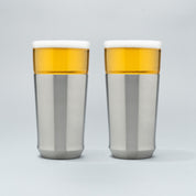 Two Elevated Craft Hybrid Pint Glasses in brushed stainless finish filled with cold beer to the top of their rims