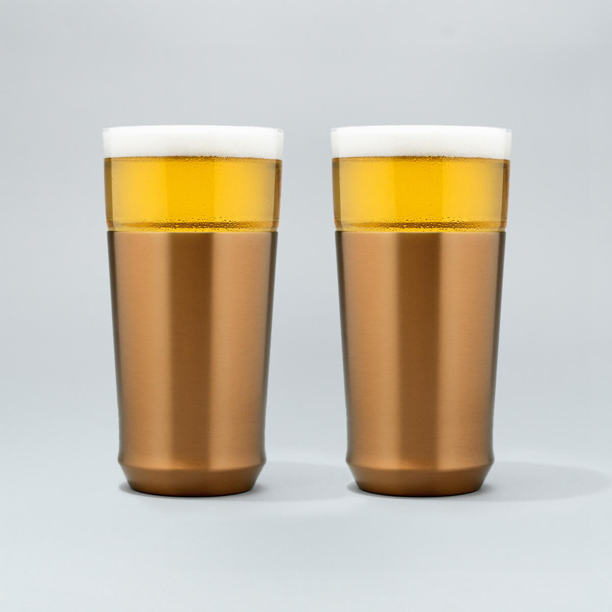 Two Elevated Craft hybrid pint glasses in brushed copper finish full of cold beer