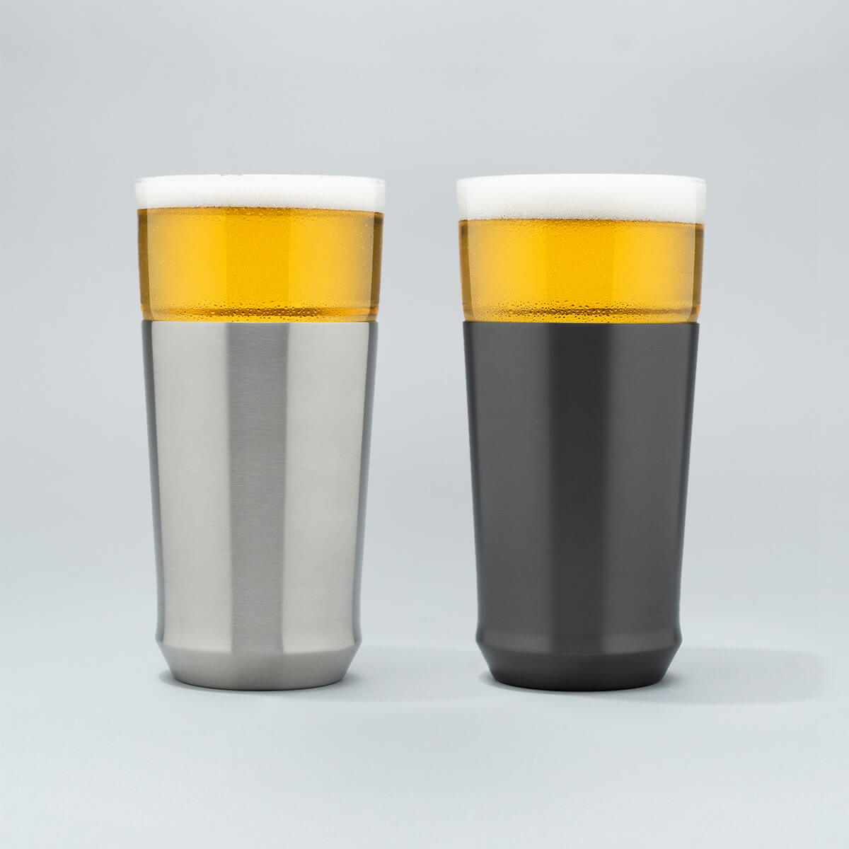 The Elevated Craft Hybrid Pint Glass in brushed stainless finish next to a hybrid pint glass in gunmetal black finish