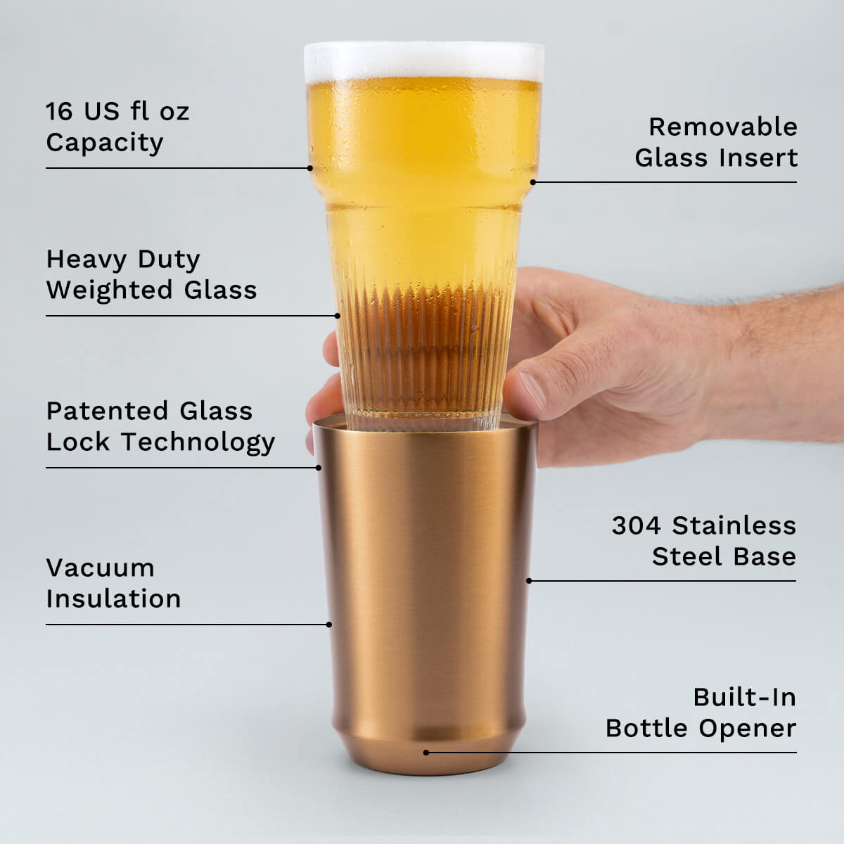 Hand holding glass insert of Elevated Craft Brushed Copper Hybrid Pint Glass above the steel base with feature callouts
