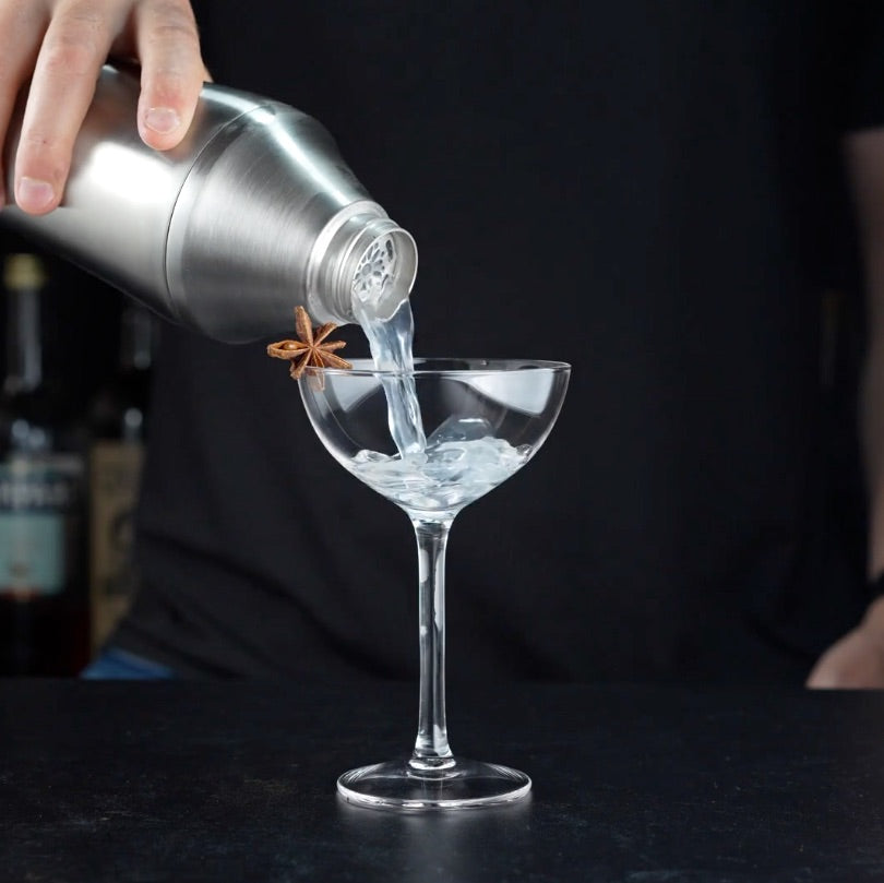 Stainless Steel Elevated Craft Hybrid Cocktail Shaker pouring cocktail into coupe glass with a star anise garnish