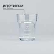 Clear glass tumbler with branding on a light gray background