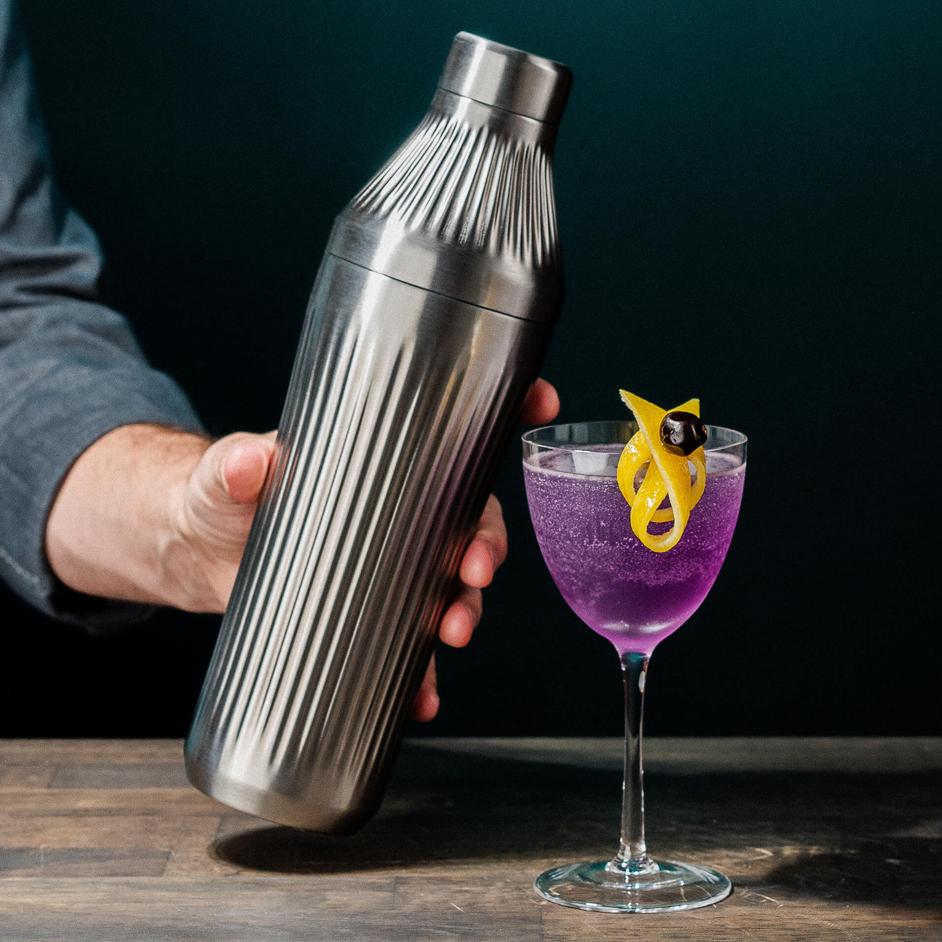 Stainless Steel Cocktail Shaker with a Aviation Cocktail next to it 