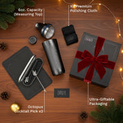 Gifting set with cocktail pick, measuring top, and polishing cloth on a wooden surface.