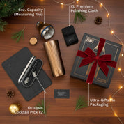 Gifting set with cocktail items on a wooden surface, featuring a tumbler, packaging, and decorative elements.