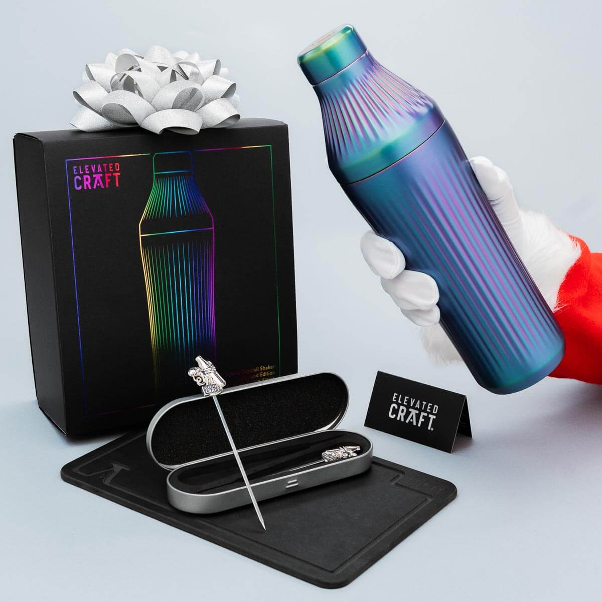 Colorful cocktail shaker with packaging, tools, and card on a light gray background