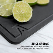 Detail Photo of a juice groove the elevated craft wood fiber garnish board also showing cut limes on a white marble 