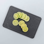 Photo of cut limes on a white marble counter using the elevated craft wood fiber garnish board