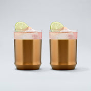 two brushed copper Elevated Craft hybrid cocktail glasses filled with a bright pink cocktail large ice cubes and lime wheel garnishes