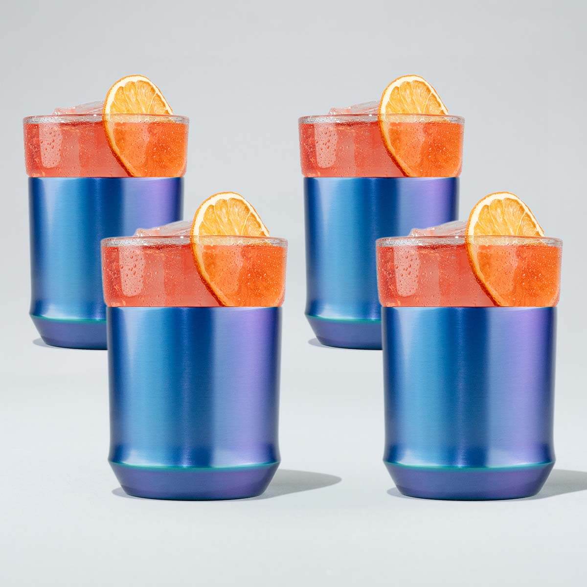 Four blue and purple tumblers with orange slices on a light gray background