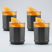 four gunmetal black finish Elevated Craft hybrid cocktail glasses filled with amber cocktails large ice cubes and garnished with orange peels
