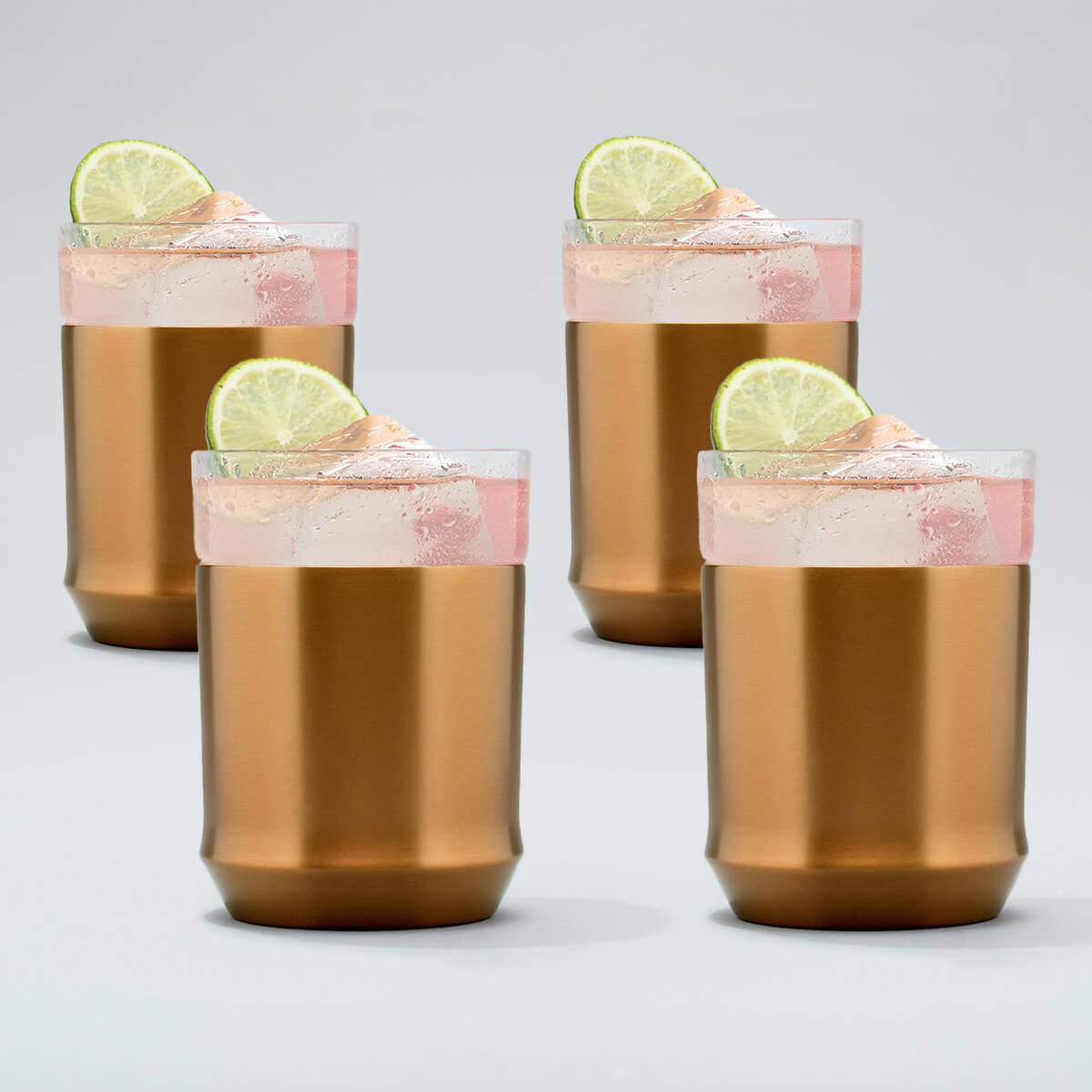 four brushed copper Elevated Craft hybrid cocktail glasses filled with bright pink cocktails large ice cubes and lime wheel garnishes