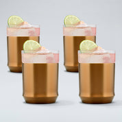 four brushed copper Elevated Craft hybrid cocktail glasses filled with bright pink cocktails large ice cubes and lime wheel garnishes