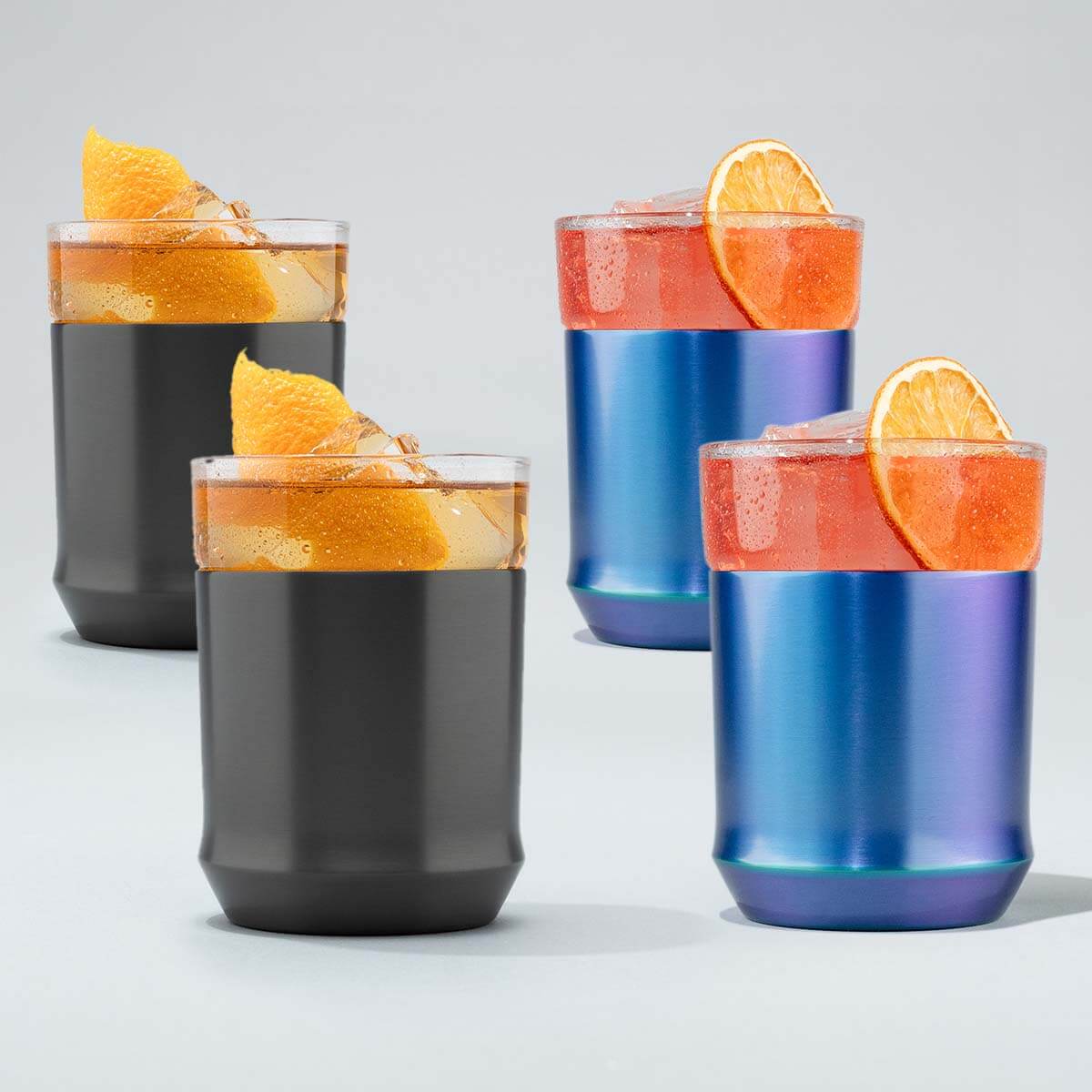 Four insulated tumblers with colorful drinks and orange slices on a light gray background
