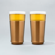 Two Elevated Craft hybrid pint glasses in brushed copper finish full of cold beer