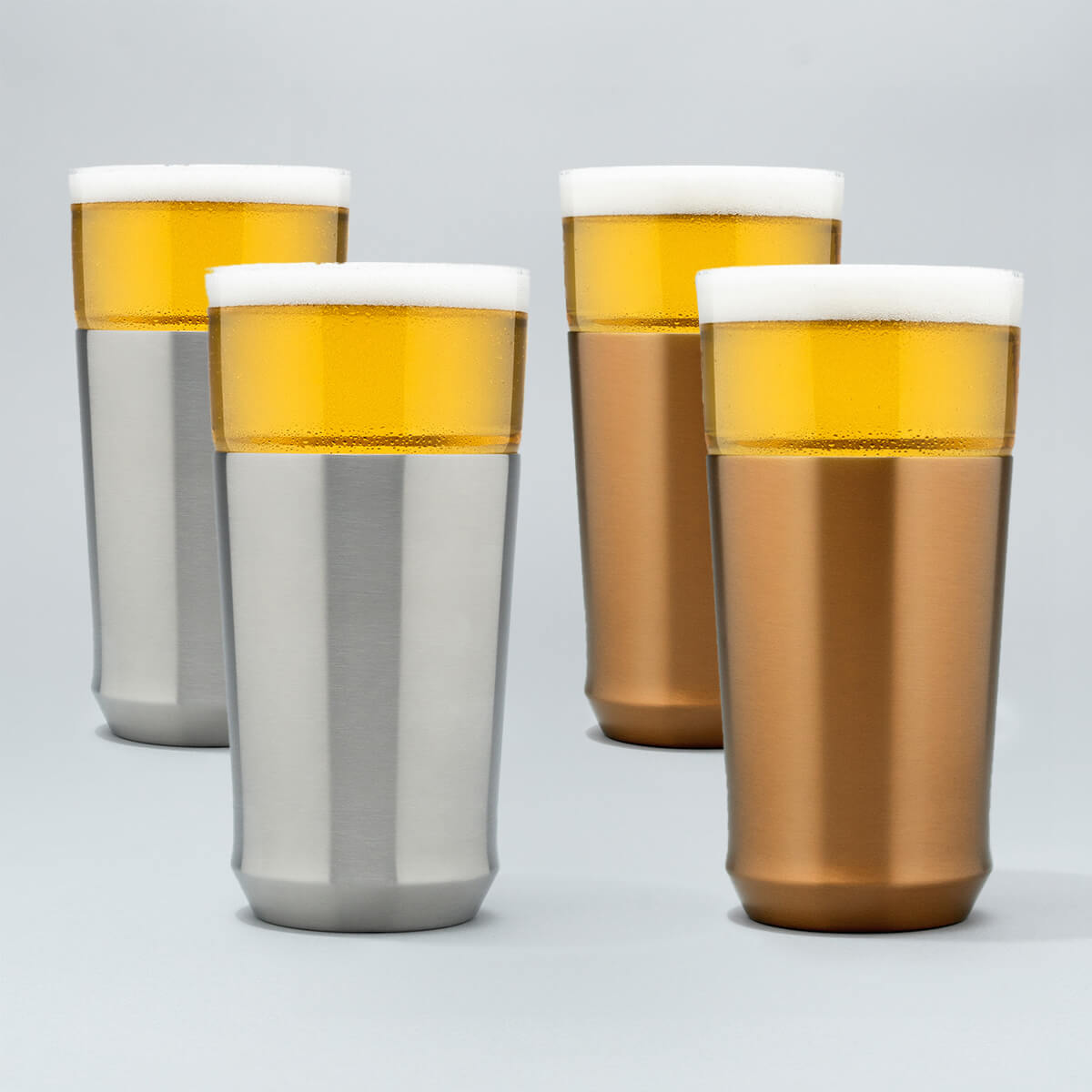Two Elevated Craft brushed stainless hybrid pint glasses filled with cold beer next to two brushed copper hybrid pint glasses filled with cold beer