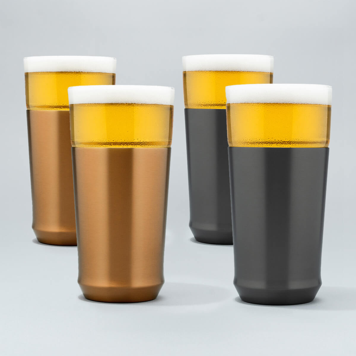 Two Elevated Craft brushed copper hybrid pint glasses filled with cold beer next to two gunmetal black hybrid pint glasses filled with cold beer