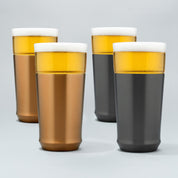Two Elevated Craft brushed copper hybrid pint glasses filled with cold beer next to two gunmetal black hybrid pint glasses filled with cold beer
