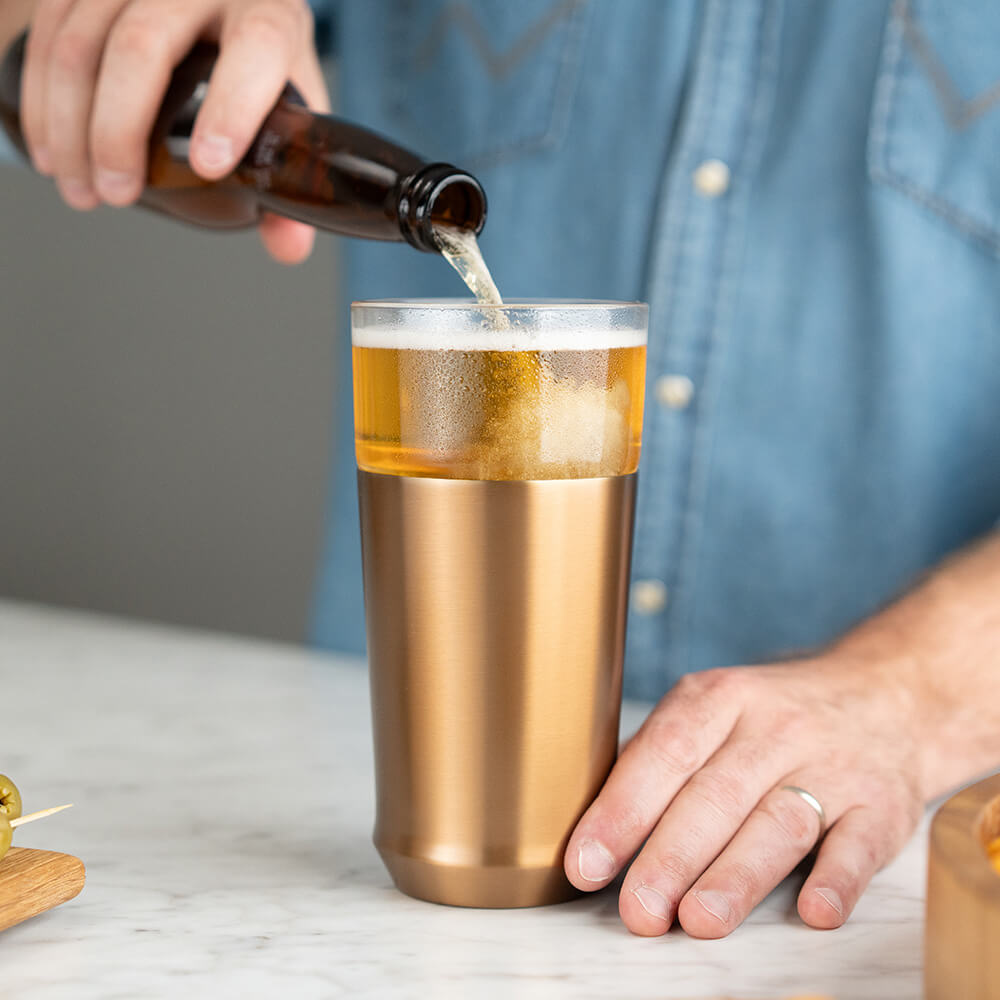 Hand pouring beer from bottle into the Brushed Copper Elevated Craft Hybrid Pint Glass