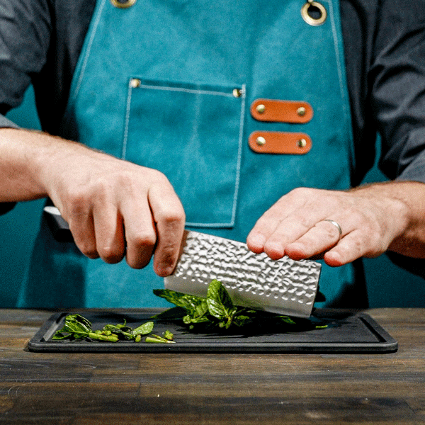 Person using a nakiri knife on a wooden surface