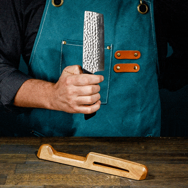 Person turning a nakiri knife, showing the hammered finish on the blade.  