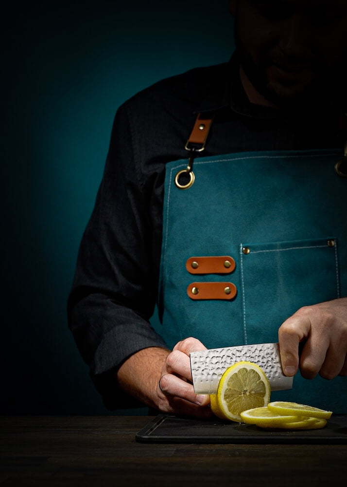 man slicing a lemon with a knife on a cutting board