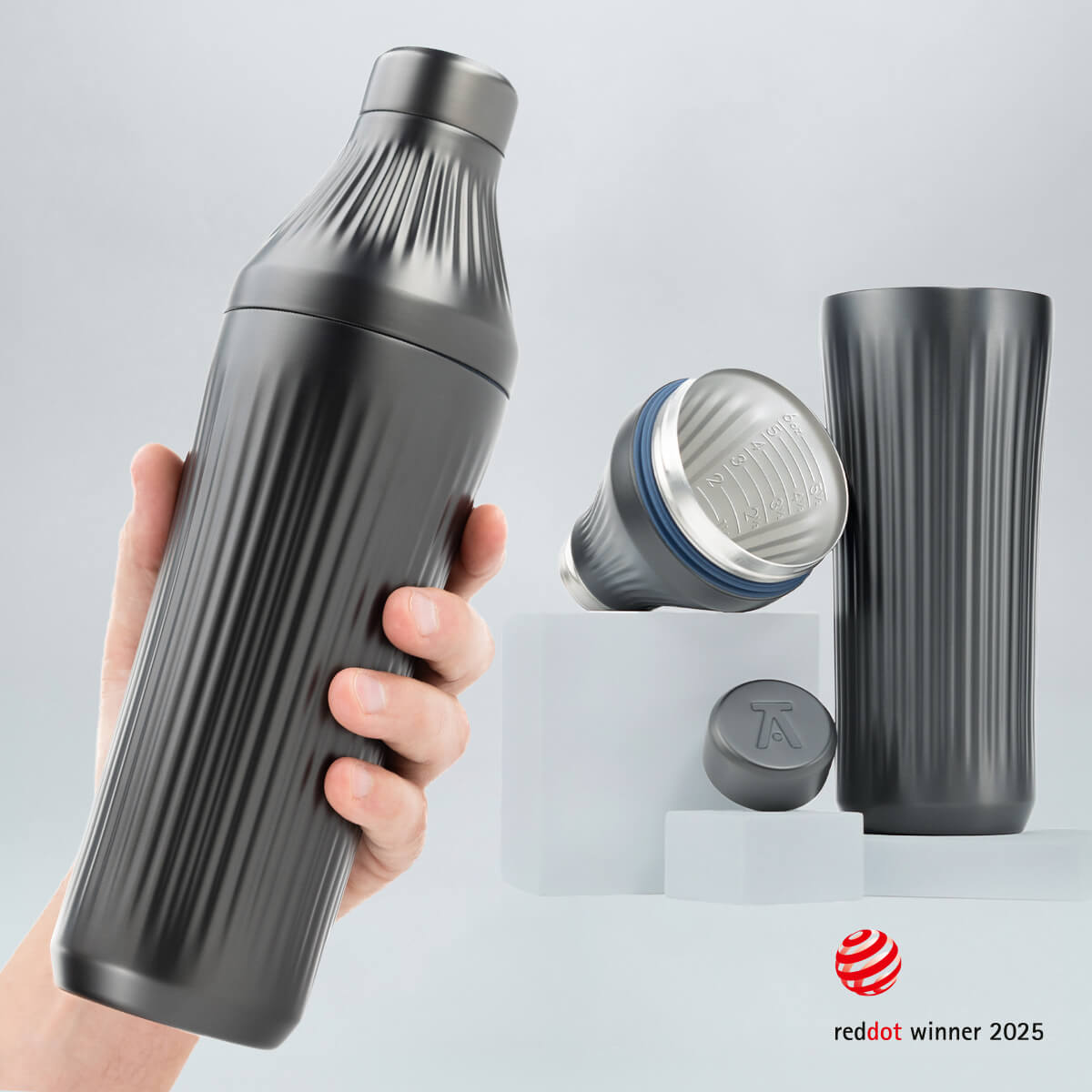 Hand holding a Gunmetal Black Diamond Edition Hybrid Cocktail Shaker with another image of the shaker taken apart to show the parts separate on gray background with RedDot Winner 2025 logo overlay