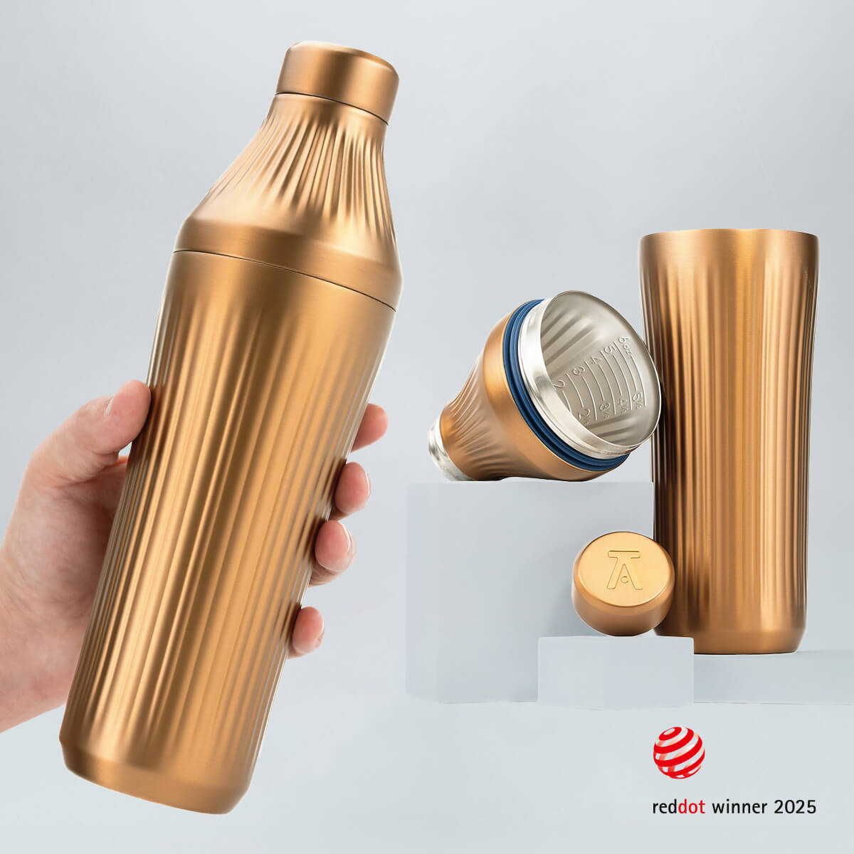 Hand holding a Brushed Copper Diamond Edition Hybrid Cocktail Shaker with another image of the shaker taken apart to show the parts separate on gray background with RedDot Winner 2025 logo overlay