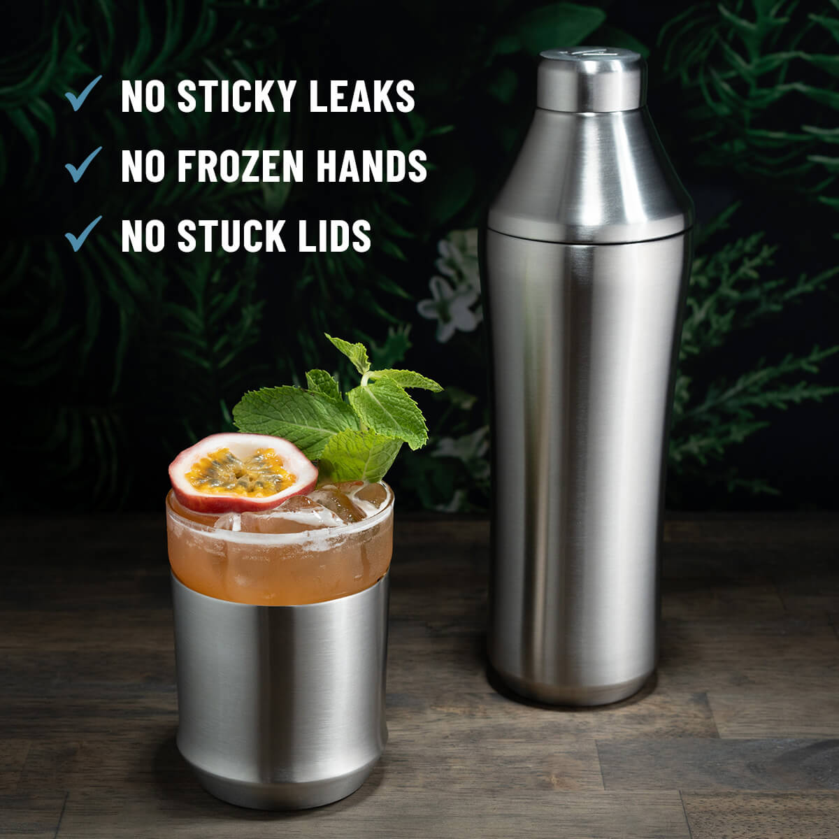 Elevated Craft Brushed Stainless Hybrid Cocktail Shaker next to orange cocktail in the Hybrid Cocktail Glass topped with passionfruit and mint with callouts "No sticky leaks, no frozen hands, no stuck lids"