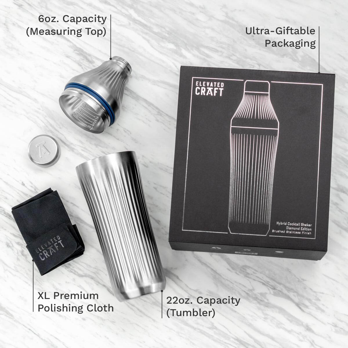 Metallic cocktail shaker set with packaging and accessories on a light wooden surface