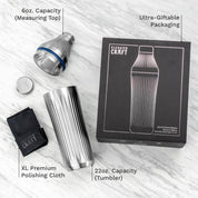 Metallic cocktail shaker set with packaging and accessories on a light wooden surface