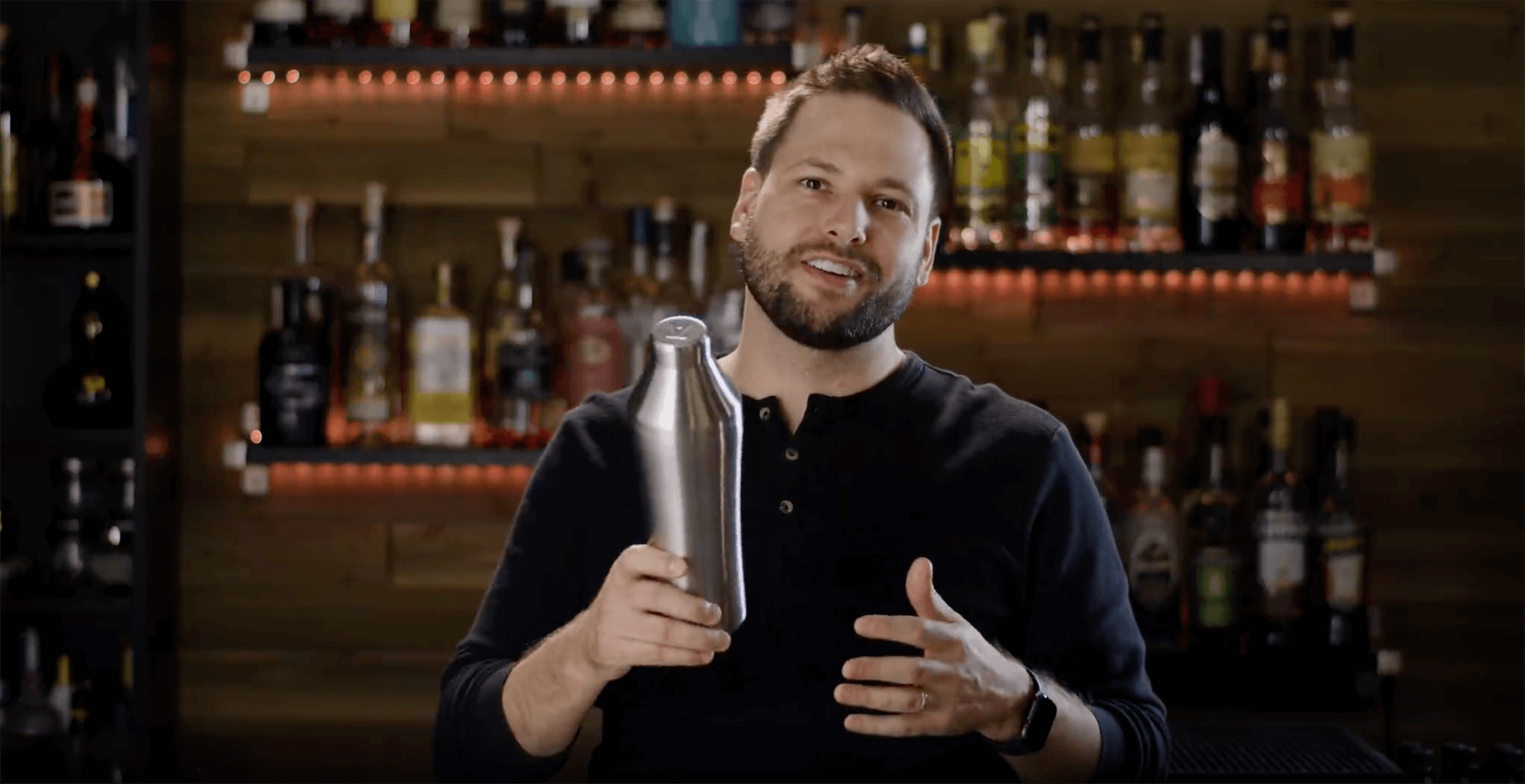 Preview of Adam Craft talking about the Elevated Craft Hybrid Cocktail Shaker in front of a bar wall with bottles