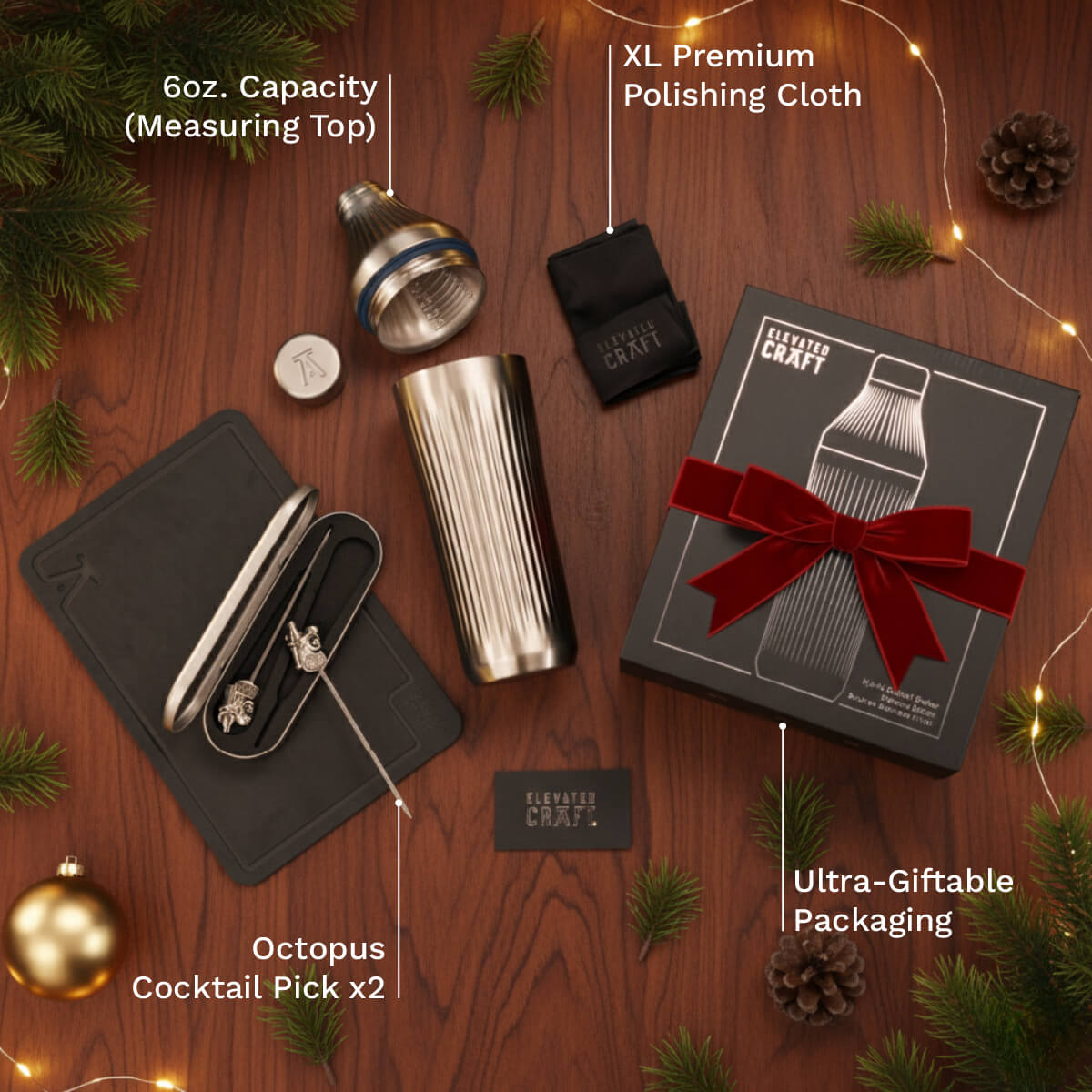 Gifting set with cocktail shaker, packaging, and accessories on a wooden surface with Christmas decorations.