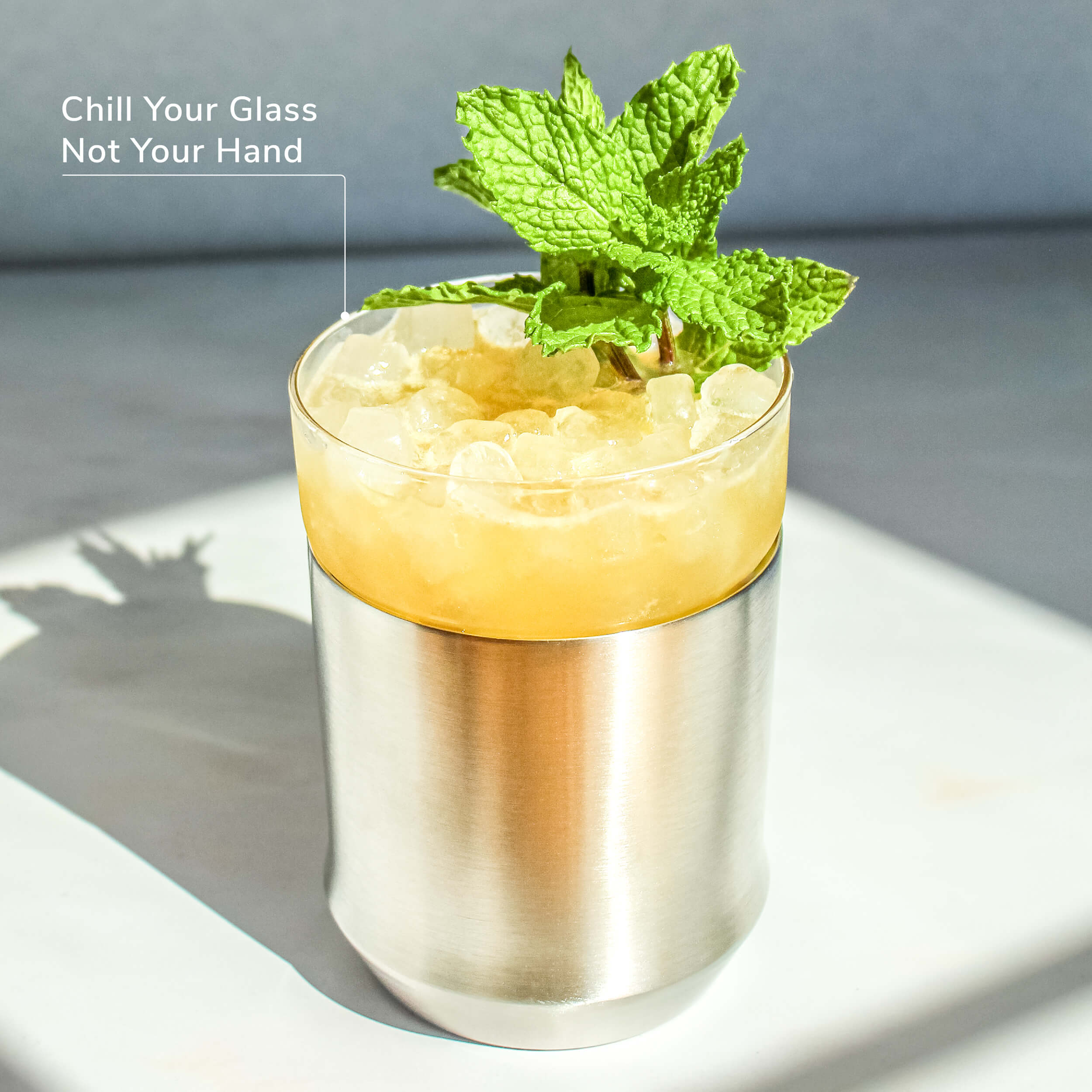 Hybrid Cocktail Glass in Brushed Stainless finish filled with bright yellow cocktail garnished with mint