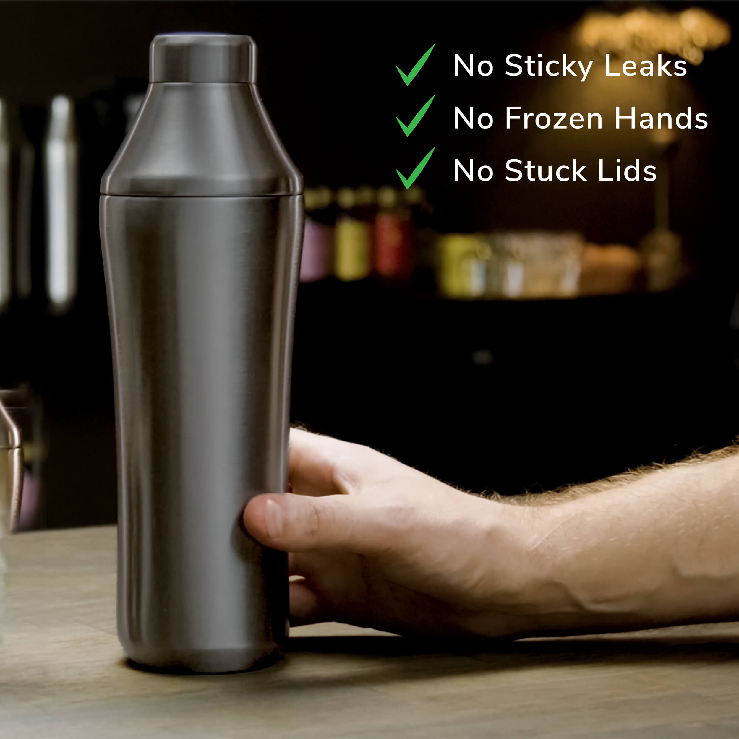 Hand holding Gunmetal Black Elevated Craft Hybrid Cocktail Shaker on bar top