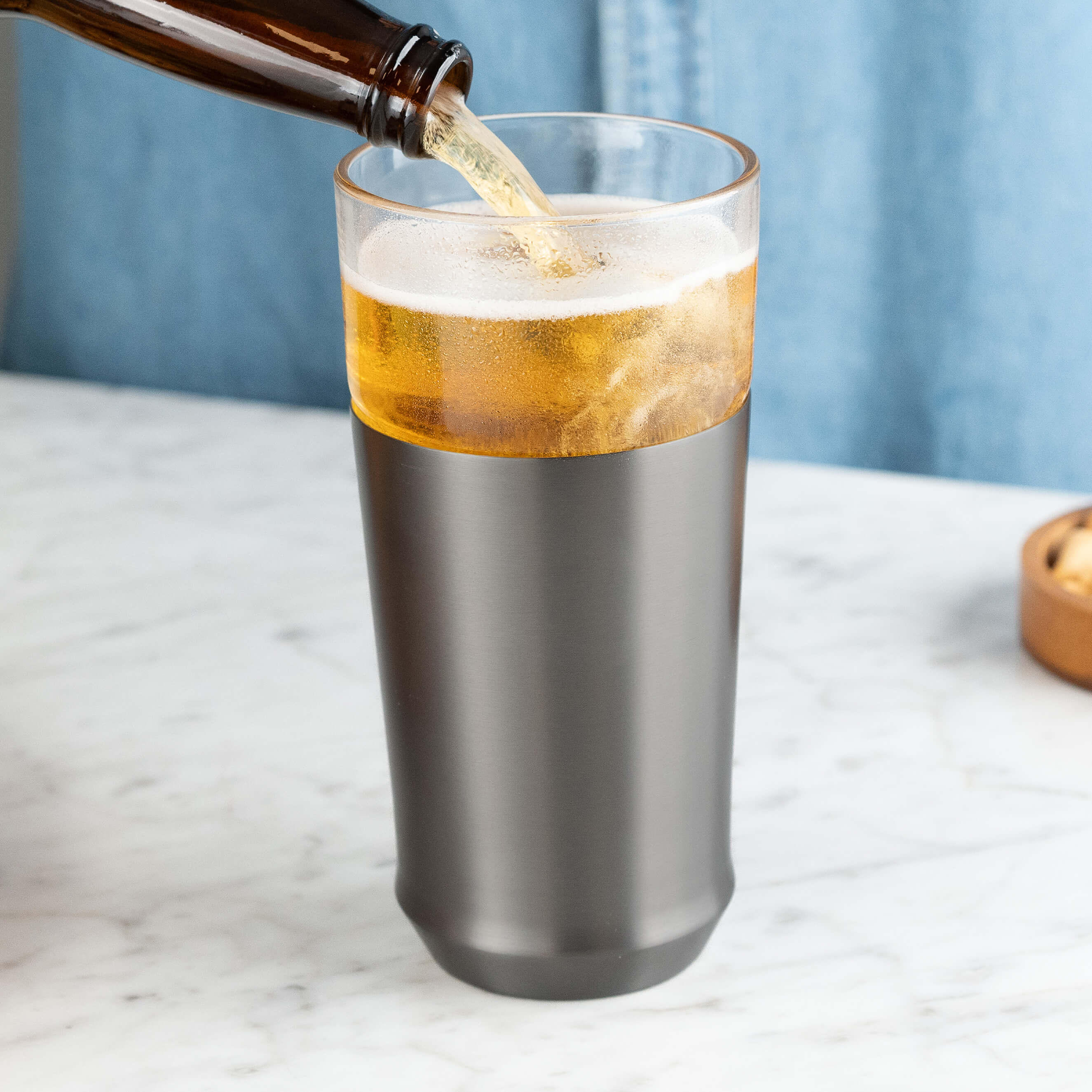 Person pouring cold beer from a bottle into the Elevated Craft Hybrid Pint Glass in gunmetal black finish