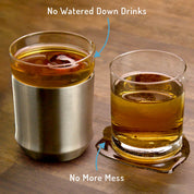 The Elevated Craft Hybrid Cocktail Glass filled with an amber cocktail and ice sphere sitting left of a traditional lowball glass filled with a watered down cocktail lying in a condensation puddle